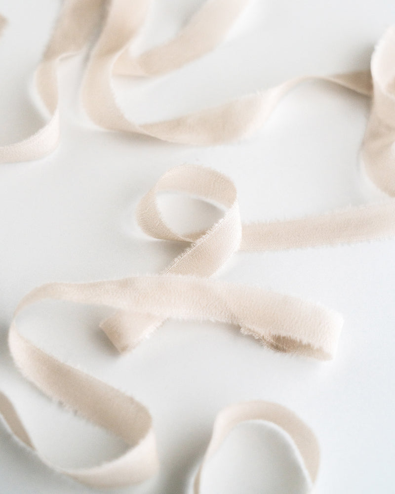 Tono + co Silk Ribbon Trim in Bone. Perfect for stationary styling, boutonnieres, and detail work. Find your inspiration through color and silk. Lovingly hand-dyed in Santa Ana, California and available in 24 signature colors. Check out our website for more styling, flat-lay, and color tips.