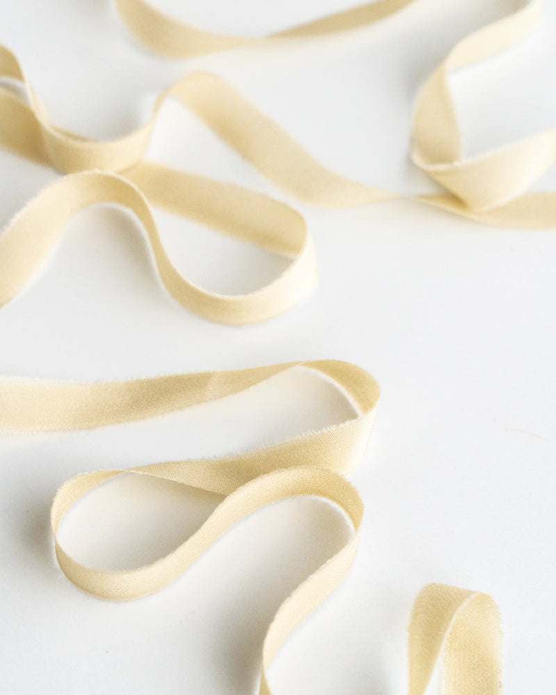 Tono + co Silk Ribbon Trim in Cream. Perfect for stationary styling, boutonnieres, and detail work. Find your inspiration through color and silk. Lovingly hand-dyed in Santa Ana, California and available in 24 signature colors. Check out our website for more styling, flat-lay, and color tips.